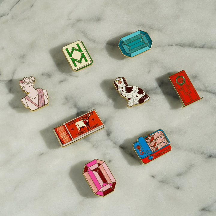 Collection of Go Stitch Studio needle minders with enamel designs and gold accents