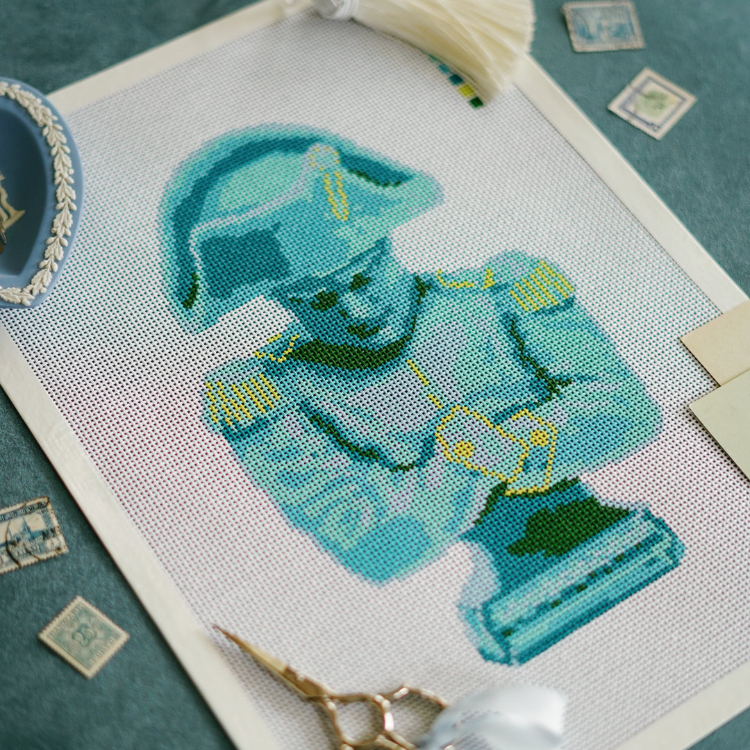Close-up of Napoleon needlepoint canvas showing blue and chartreuse stitch-painted detail