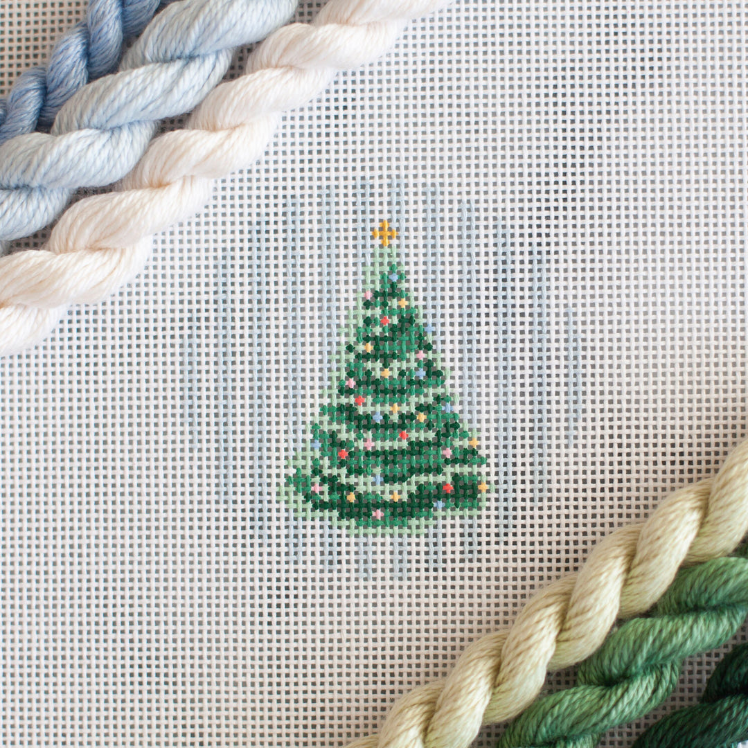 needlepoint canvas of a Christmas Tree on blue tripes in a small circle