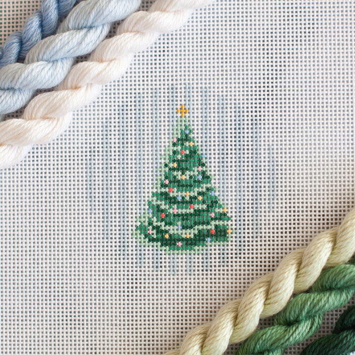 needlepoint canvas of a Christmas Tree on blue tripes in a small circle